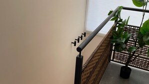 A staircase with a wooden finish, a black metal handrail, and a woven basket barrier.