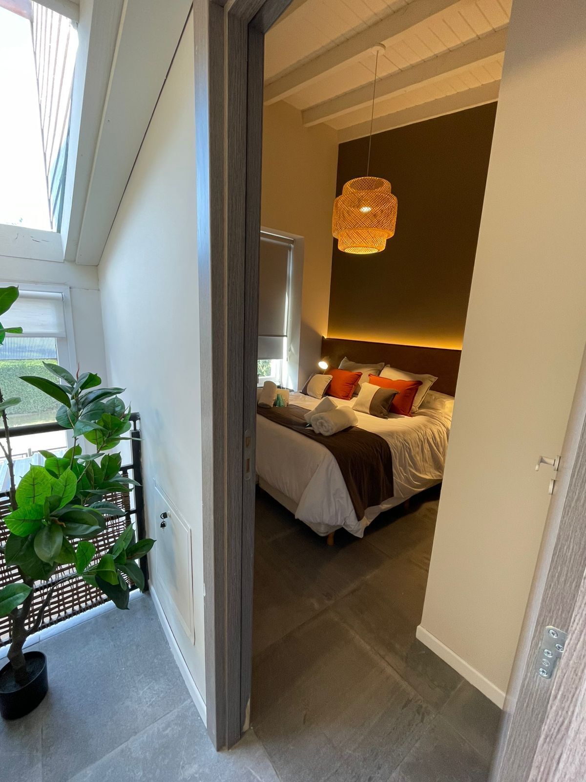 A modern bedroom with a bed, bedside table, and a hanging light fixture.
