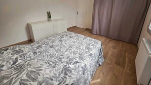 Ein Schlafzimmer mit Bett, Kommode, Tür und Vorhang.