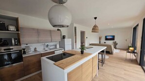 Eine moderne Küche mit Kochinsel, eingebauten Geräten und einer Essecke mit Sofa und Tisch.