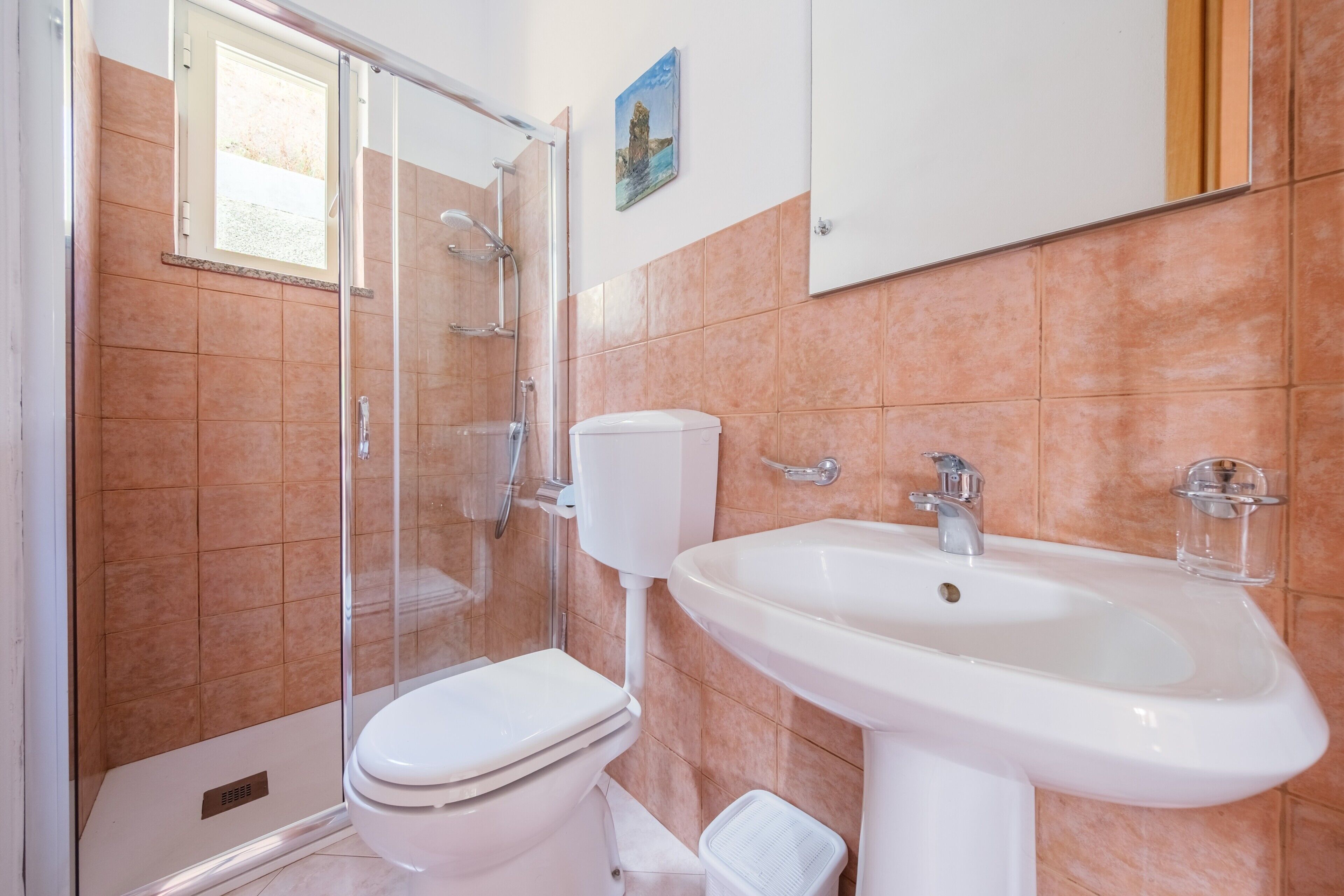 Un baño con ducha de vidrio, inodoro blanco y lavamanos blanco.
