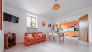 Een moderne woonkamer met een bank, televisie en een eethoek met stoelen en een tafel.