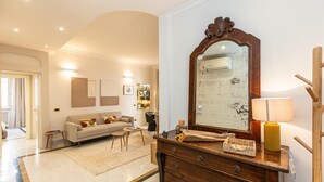 A living room with a sofa, a wooden dresser, a mirror, and a lamp. - Apartment San Trifone RiR Collection (Rome)