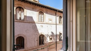 A window with a view of a building featuring arched windows and a balcony. - Apartment San Trifone RiR Collection (Rome)