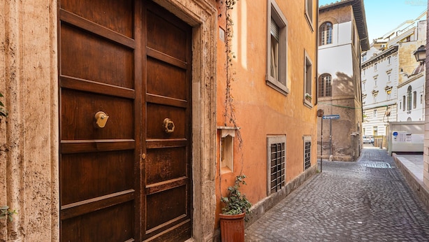 A cobblestone street with a large wooden door and a potted plant. - Apartment San Trifone RiR Collection (Rome)