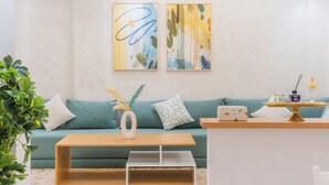 Ein modernes Wohnzimmer mit einem grünen Sofa, einem Holztisch und zwei abstrakten Bildern an der Wand.