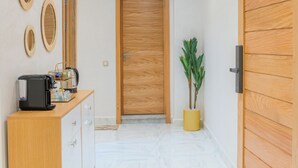 Ein Flur mit Holztür, Blumentopf und einer Rezeption mit Kaffeeautomat.