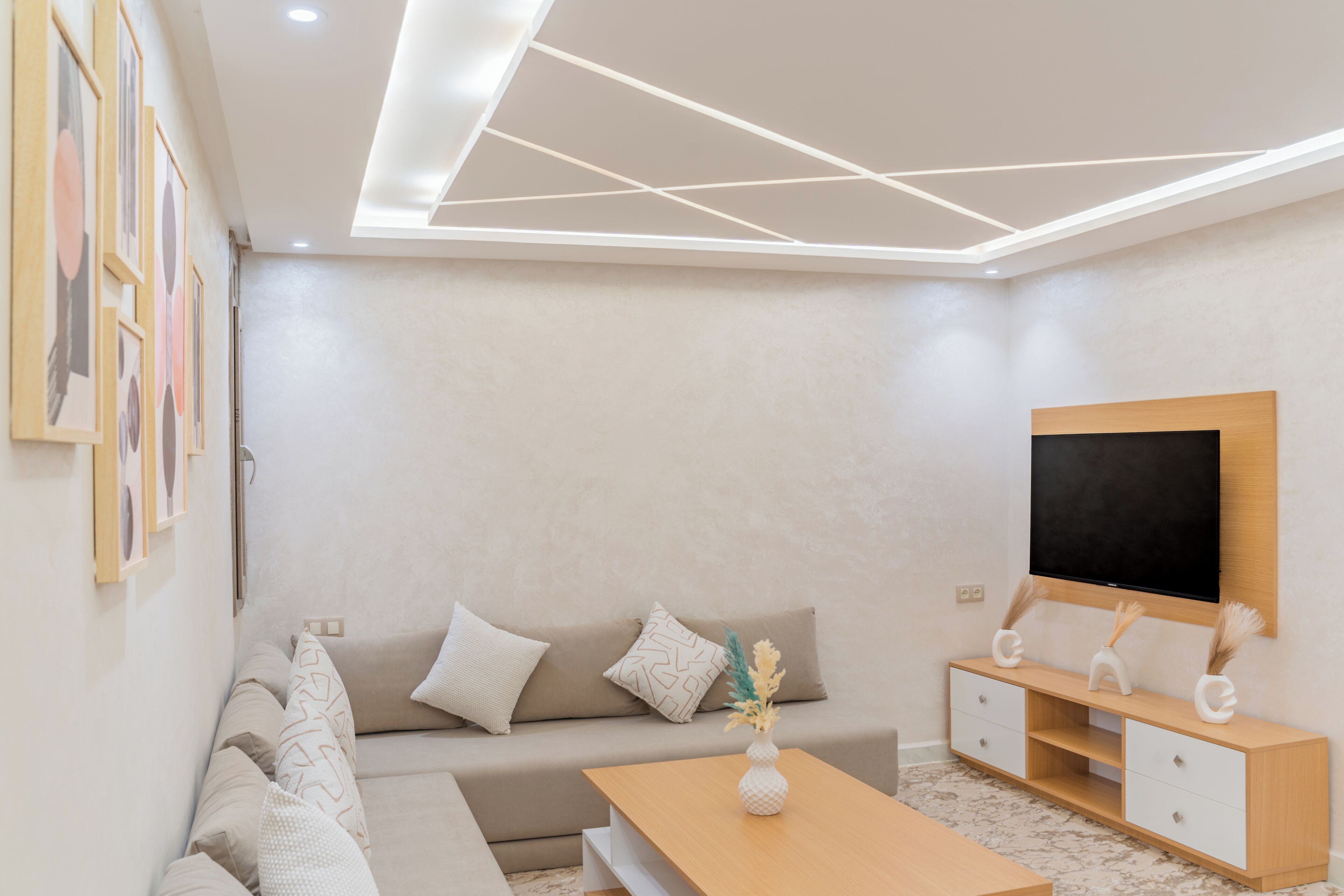 A modern living room with a sofa, coffee table, TV, and decorative vases.