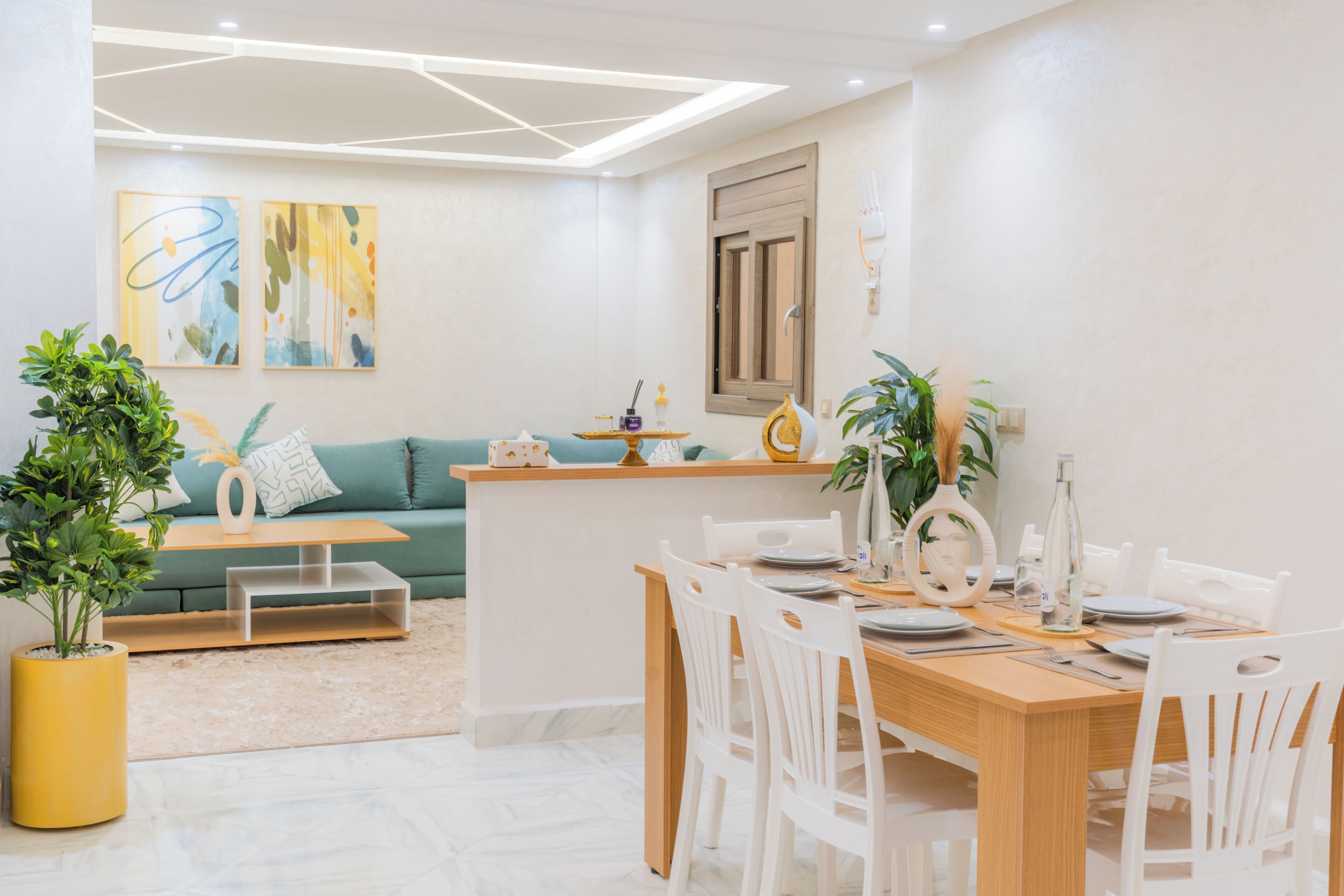 A modern dining area with a wooden table, white chairs, and a green sofa in the background.