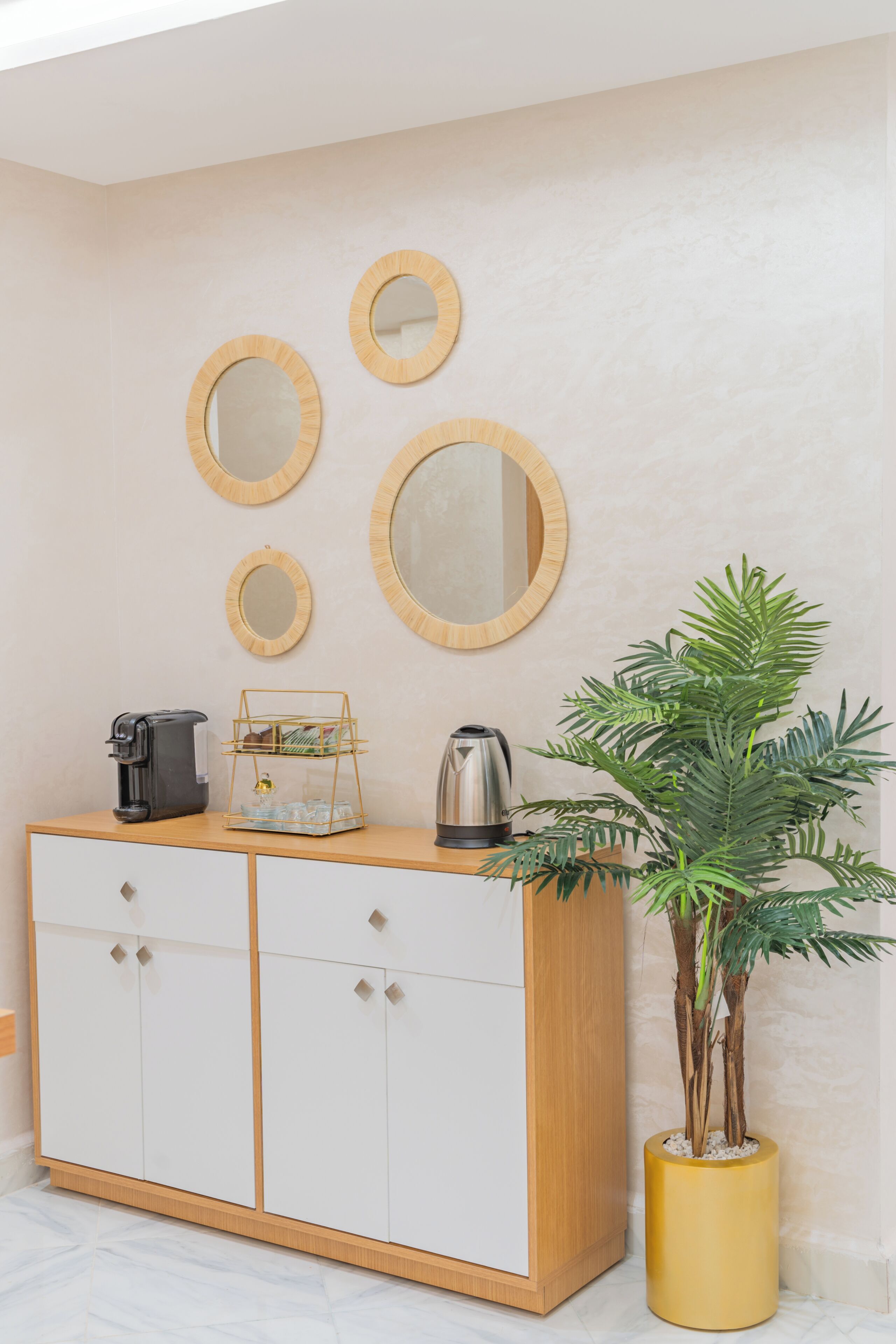 Una habitación con un armario de madera, una cafetera, un hervidor y una planta en maceta.