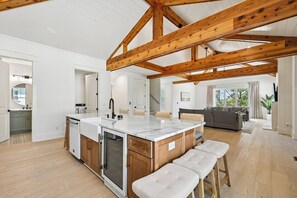Una cocina amplia con vigas de madera, una isla grande y una zona de comedor con sofá.