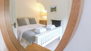 A bedroom with a bed, bedside table, lamp, and a painting on the wall. - Lumford Mill Cottage (Bakewell)