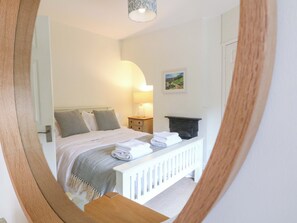 A bedroom with a bed, bedside table, lamp, and a painting on the wall. - Lumford Mill Cottage (Bakewell)