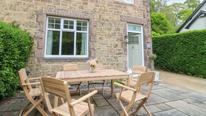 A stone building with a door marked '9', a window, and a table with chairs outside. - Lumford Mill Cottage (Bakewell)