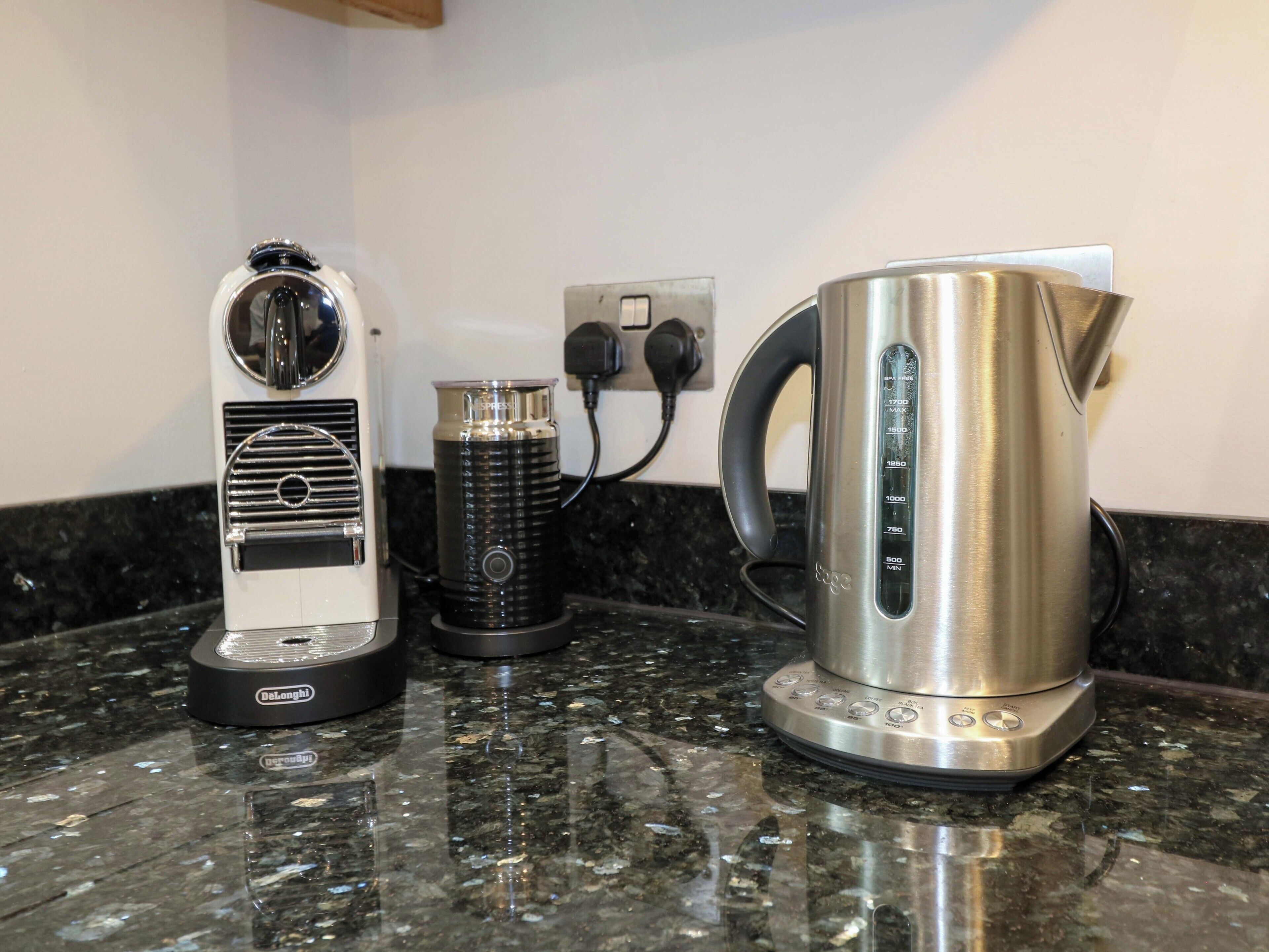 Une cuisine équipée d’une machine à café, d’une bouilloire et d’un mixeur, le tout posé sur un plan de travail en granit.