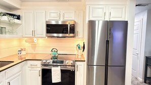A kitchen with white cabinets, a stainless steel refrigerator, a microwave, and an oven.