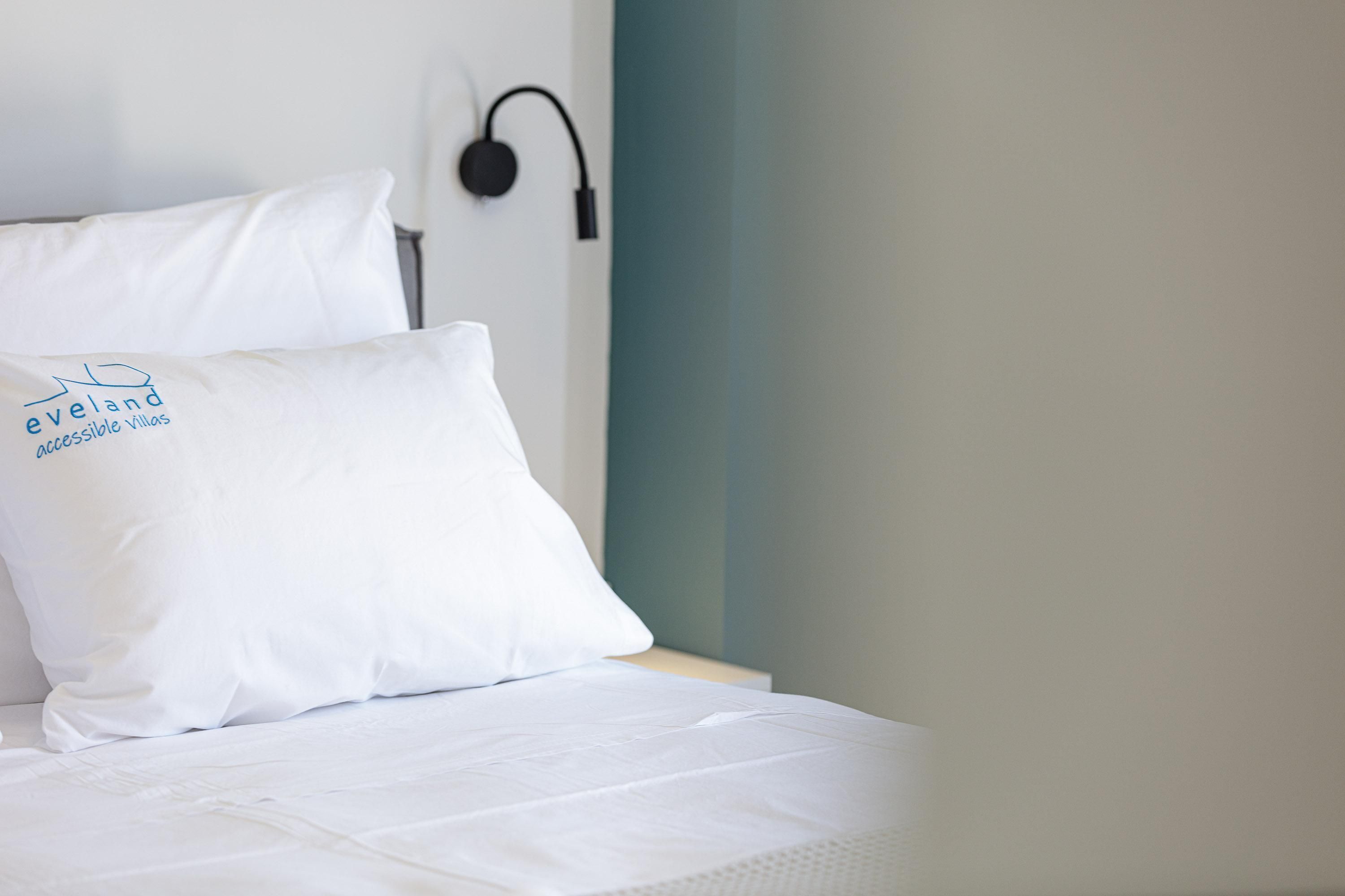 Una cama con ropa blanca y una almohada con el texto 'eveland accessible villas'.