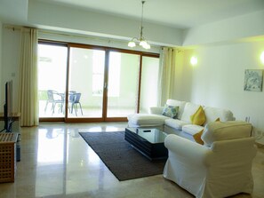 A modern living room with a sofa, armchairs, a coffee table, and a television.