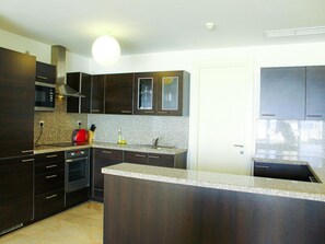 A modern kitchen with dark cabinetry, a granite countertop, and a built-in oven.