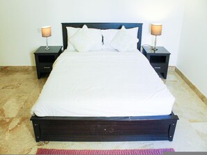A bed with a wooden frame, two bedside tables, and two lamps. - Spacious 3-bedroom Luxury Living (As Sifah)