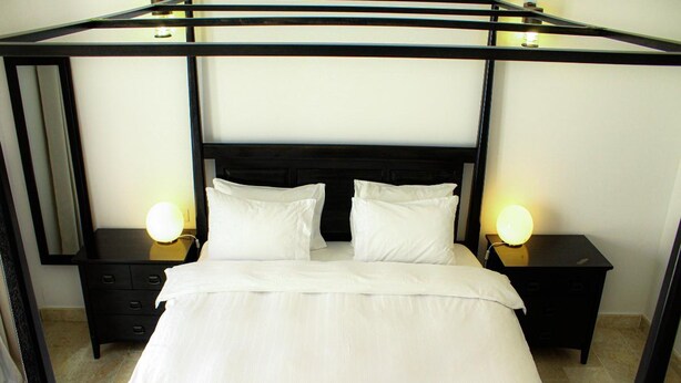 A bed with a black metal frame, white bedding, and two bedside lamps. - Modern 2-bedroom With Marina Views (As Sifah)