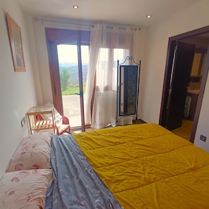 Une chambre à coucher avec un lit, une chaise, un miroir et une vue sur l’extérieur.