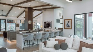 Een moderne keuken met een centraal eiland, barstoelen en een zithoek met een bank.