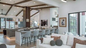Eine moderne Küche mit einer zentralen Kochinsel, Barhocker und einer Essecke mit einer Couch.