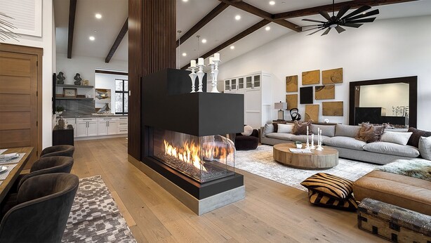 Een moderne woonkamer met een open haard, een bank, een salontafel en een eethoek met stoelen.