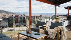Eine Terrasse mit Tisch, Stühlen, einem Grill und Blick auf eine Berglandschaft.