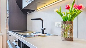 A modern kitchen with stainless steel appliances, a black faucet, and a vase with tulips on the counter. - Panoramablick Tauern by Interhome (Mittersill)
