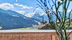 A mountain landscape with snow-capped peaks and a village below. - Panoramablick Tauern by Interhome (Mittersill)
