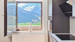 A kitchen with a large window offering a mountain view, a radiator, and modern appliances. - Panoramablick Tauern by Interhome (Mittersill)
