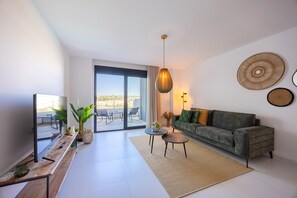 Ein modernes Wohnzimmer mit einer Couch, einem Couchtisch, einem Fernseher und einem großen Fenster mit Blick.