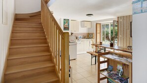 Una escalera de madera que lleva a una cocina con comedor y un tablón de anuncios.
