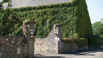 Ein Steinhaus mit steiler Satteldachform, bewachsen mit Efeu, und einem Schild mit der Aufschrift 'Chambres Dits de Vignes'.