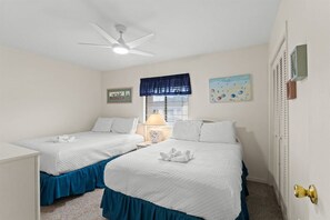 A hotel room with two beds, a ceiling fan, a window with blinds, and wall art. - Gulf Highlands 2BR 11 Pools Beach Access Sleeps 6 (Panama City Beach)