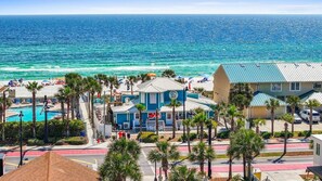 Un hôtel en bord de mer doté d’une piscine, de palmiers et offrant une vue sur l’océan.