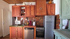 Una cucina con mobili in legno, un forno a microonde, una macchina da caffè, un frigorifero e una lavastoviglie.