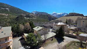 Zona residenziale con edifici, un parcheggio e montagne sullo sfondo.