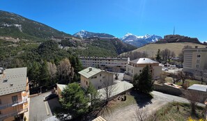 A residential area with buildings, a parking lot, and a mountainous backdrop. - Spacious Briançon Flat with Balcony (Briançon)