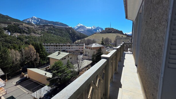 Zona residenziale con edifici, un balcone e montagne sullo sfondo.