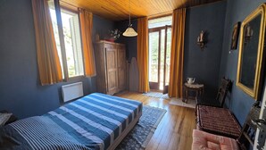 Una stanza con un letto, un armadietto di legno, un tavolino con teiera e una sedia in vimini.