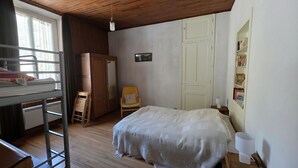 Makuuhuoneessa on kerrossänky, tuoli, yöpöytä, lamppu, vaatekaappi ja hylly, jossa on kirjoja.