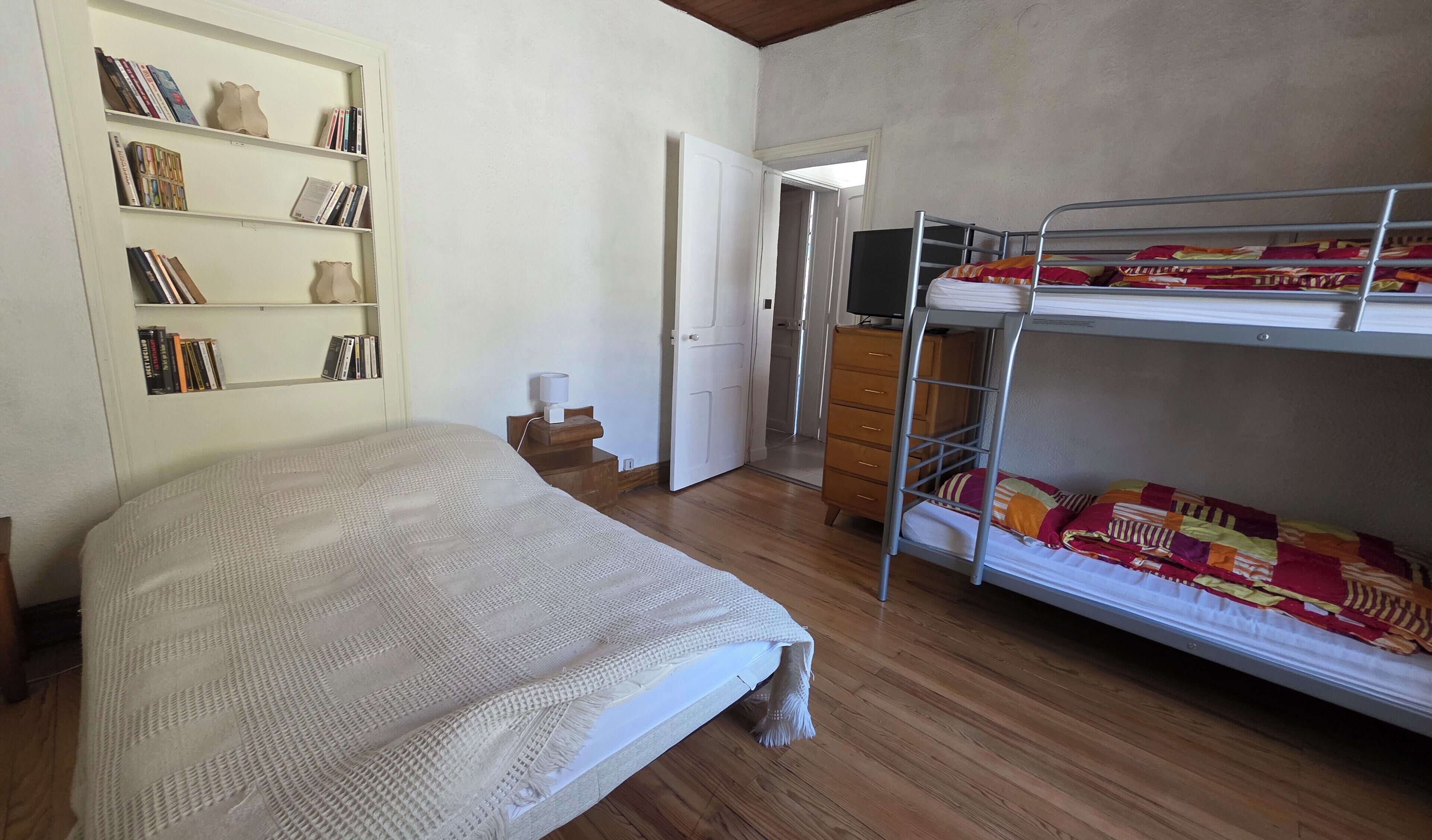 A bedroom with a bunk bed, a bookshelf, a desk, and a wardrobe.