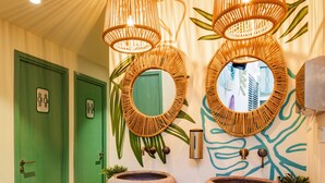 Une salle de bain avec deux portes vertes, un lavabo en pierre et une poubelle.