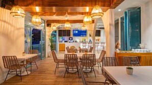 Un restaurant avec des meubles en osier, un plafond en bois et un bar situé au fond de la salle.