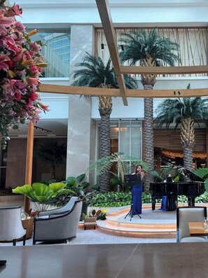 A spacious indoor atrium with a stage, seating, and a grand piano.