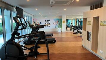 A gym with treadmills, exercise balls, and weights. There is a motivational poster on the wall and large windows.