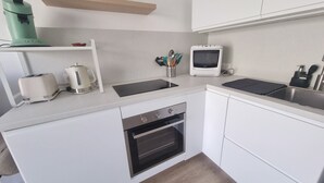 A compact kitchen with white cabinets, a built-in oven, a toaster, a kettle, and a microwave. - AC studio with balcony in central Arcachon (Arcachon)